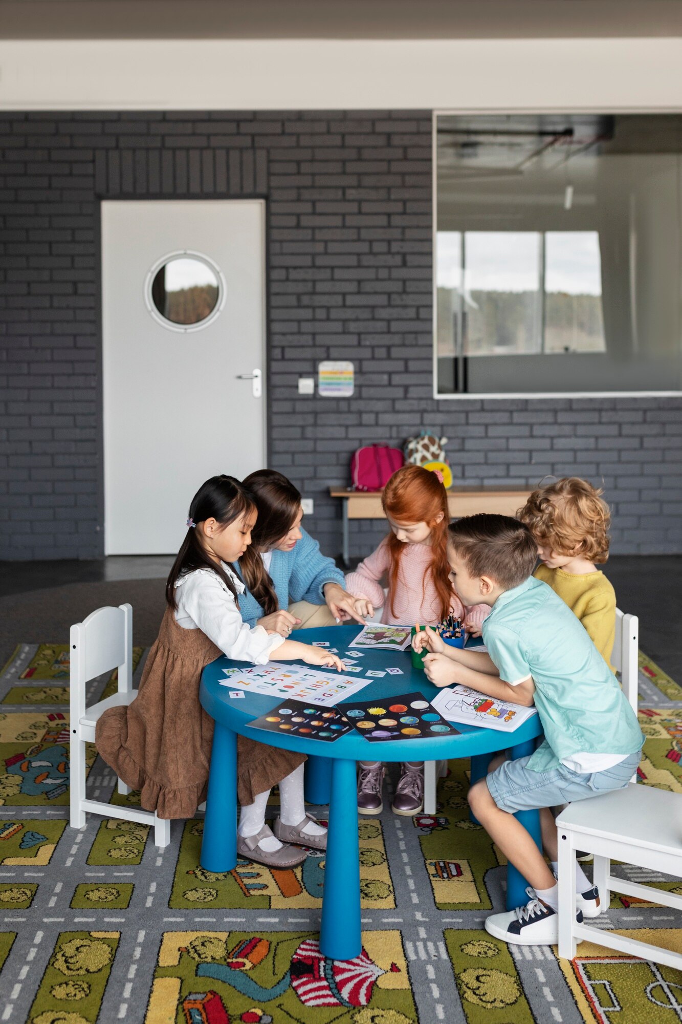 full-shot-kids-teacher-sitting-table_23-2149355204
